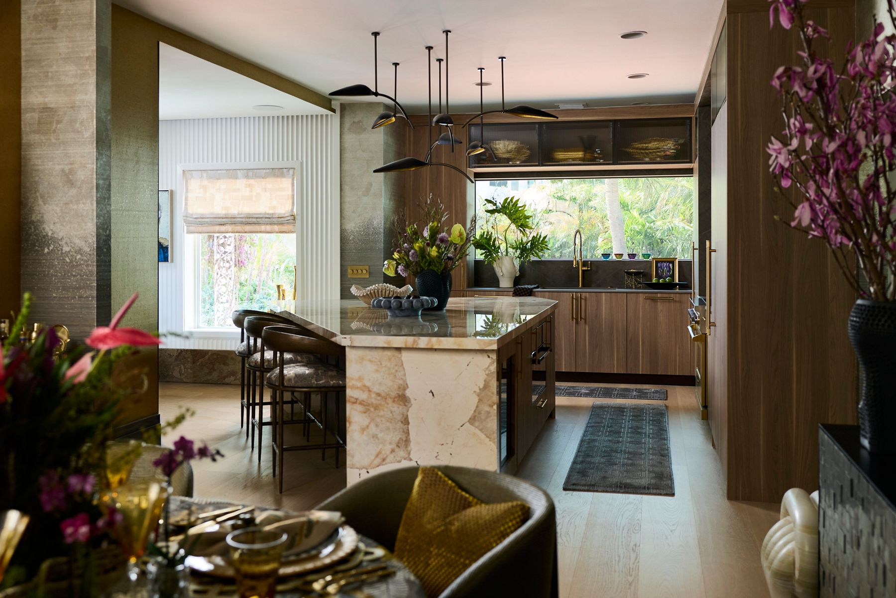 Kips Bay show house featuring a mid-century modern designed kitchen with light and medium wood cabinets and flooring, neutral marble island, and brass hardware.