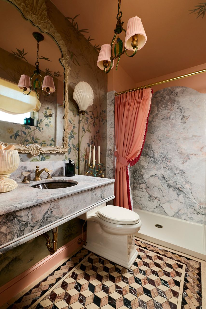 Refined, vintage-style powder room with botanical wallpaper, an ornate mirror frame, and a brass faucet.