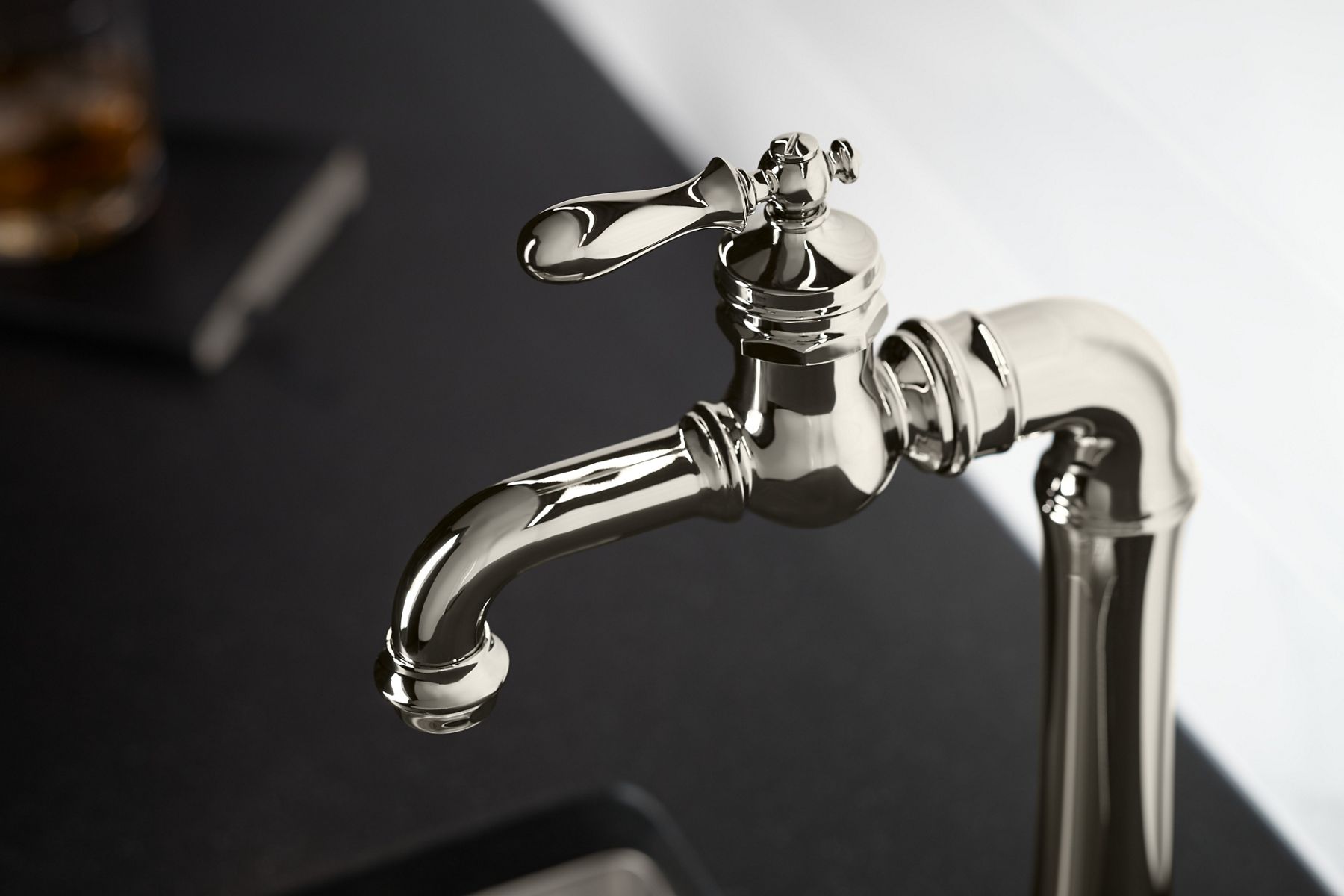 A bar faucet in polished nickel finish with traditional ornamentation and detailing.