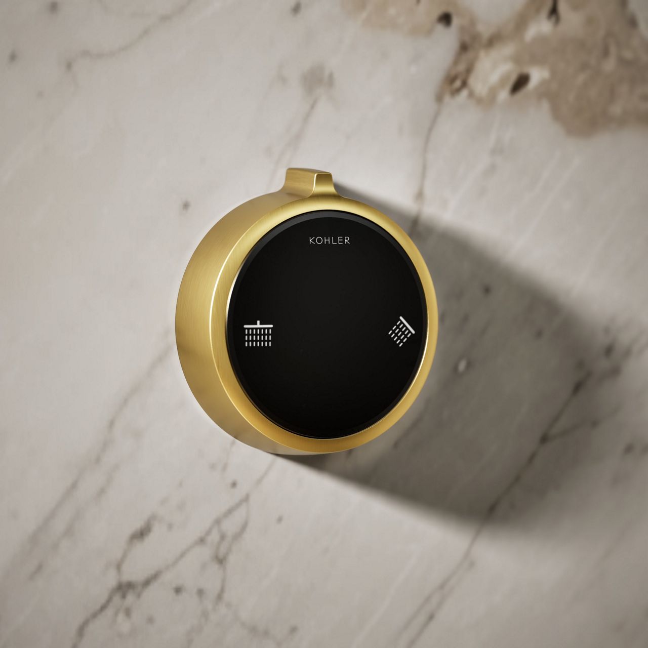 Round brushed gold smart shower control dial on marble wall