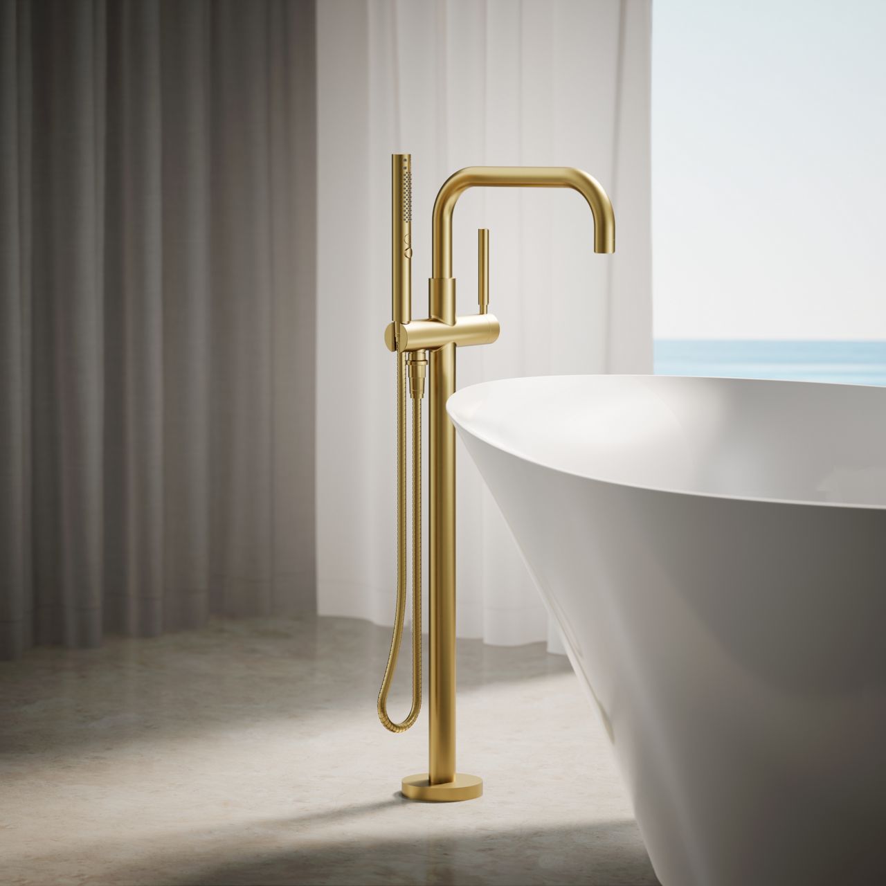 Freestanding brushed gold tub filler with hand shower beside white bathtub
