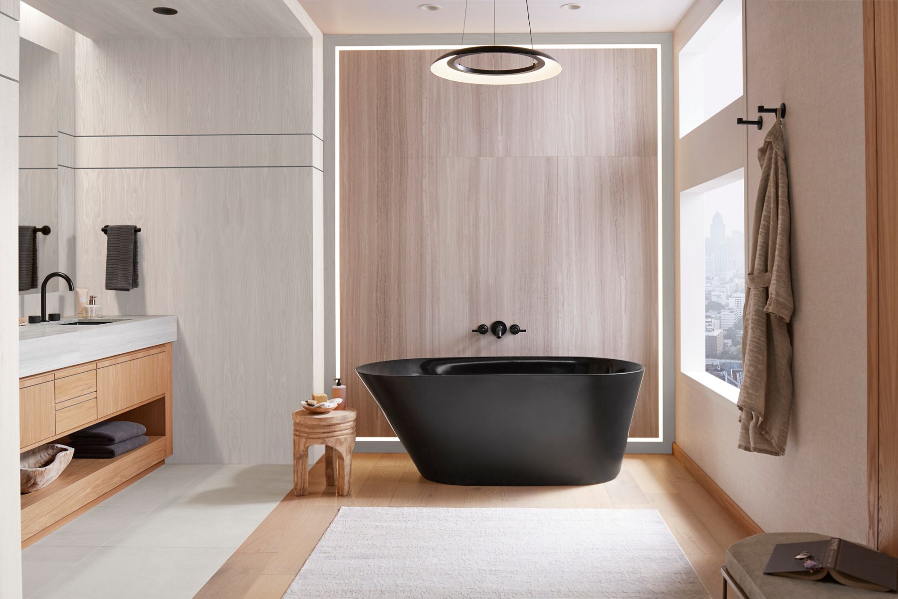 Black freestanding bathtub with wall-mounted faucet in a neutral bathroom.