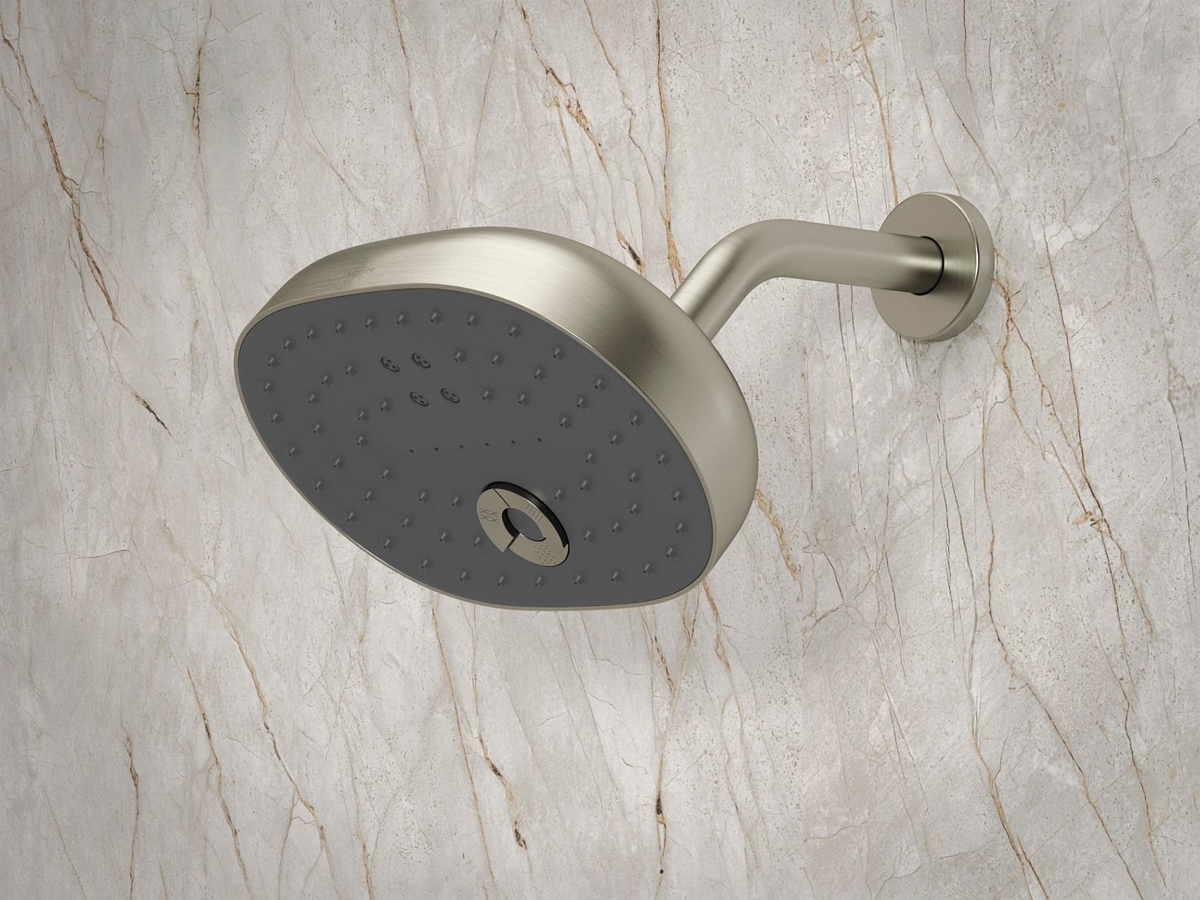 Gros plan d’une pomme de douche Kohler au fini nickel poli installée sur un mur de douche en pierre naturelle. La pomme de douche large et horizontale est présentée pour montrer les buses de pulvérisation abondantes.