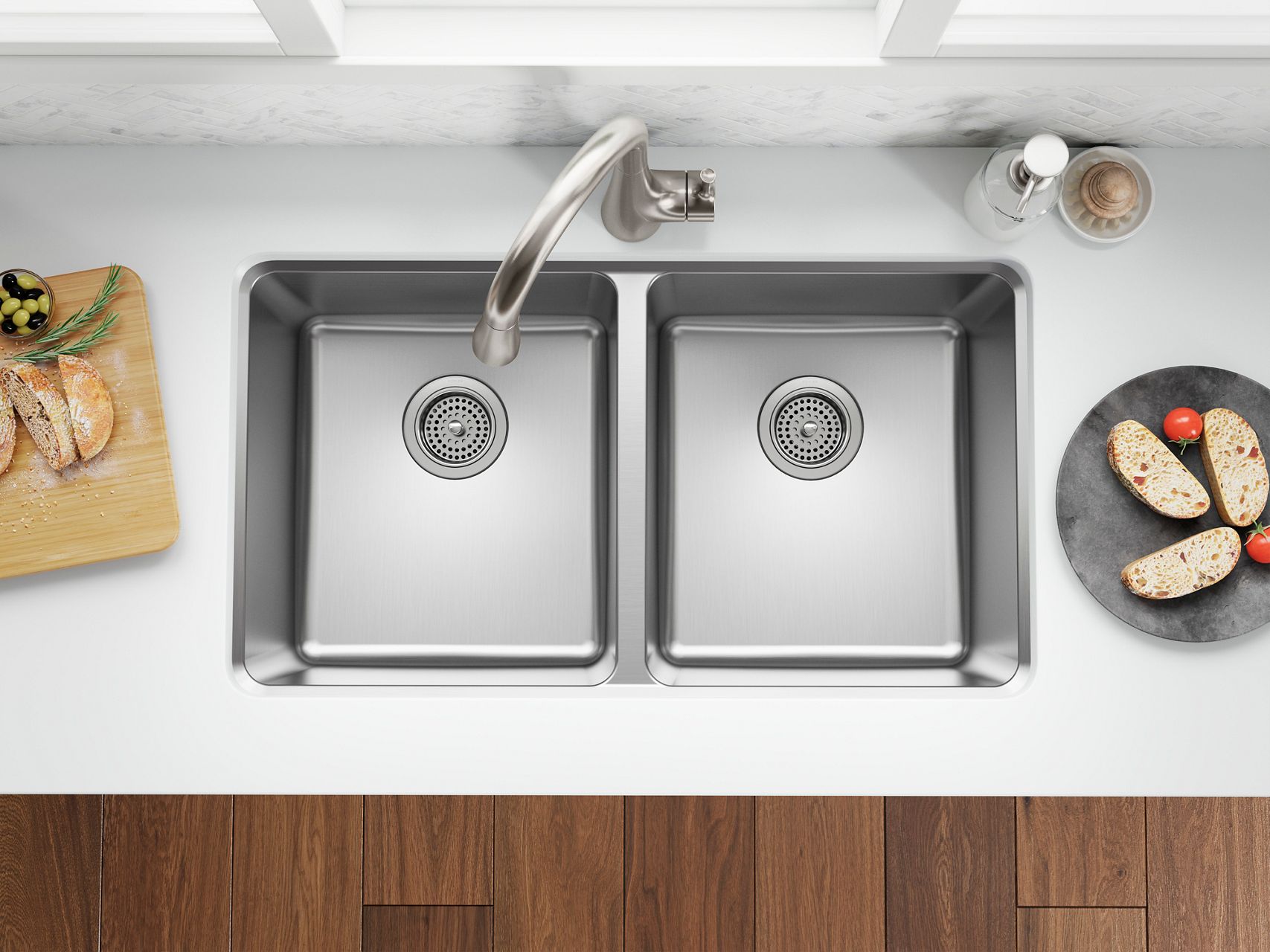 Top view of double stainless steel kitchen sink with curved faucet and bread slices on counter