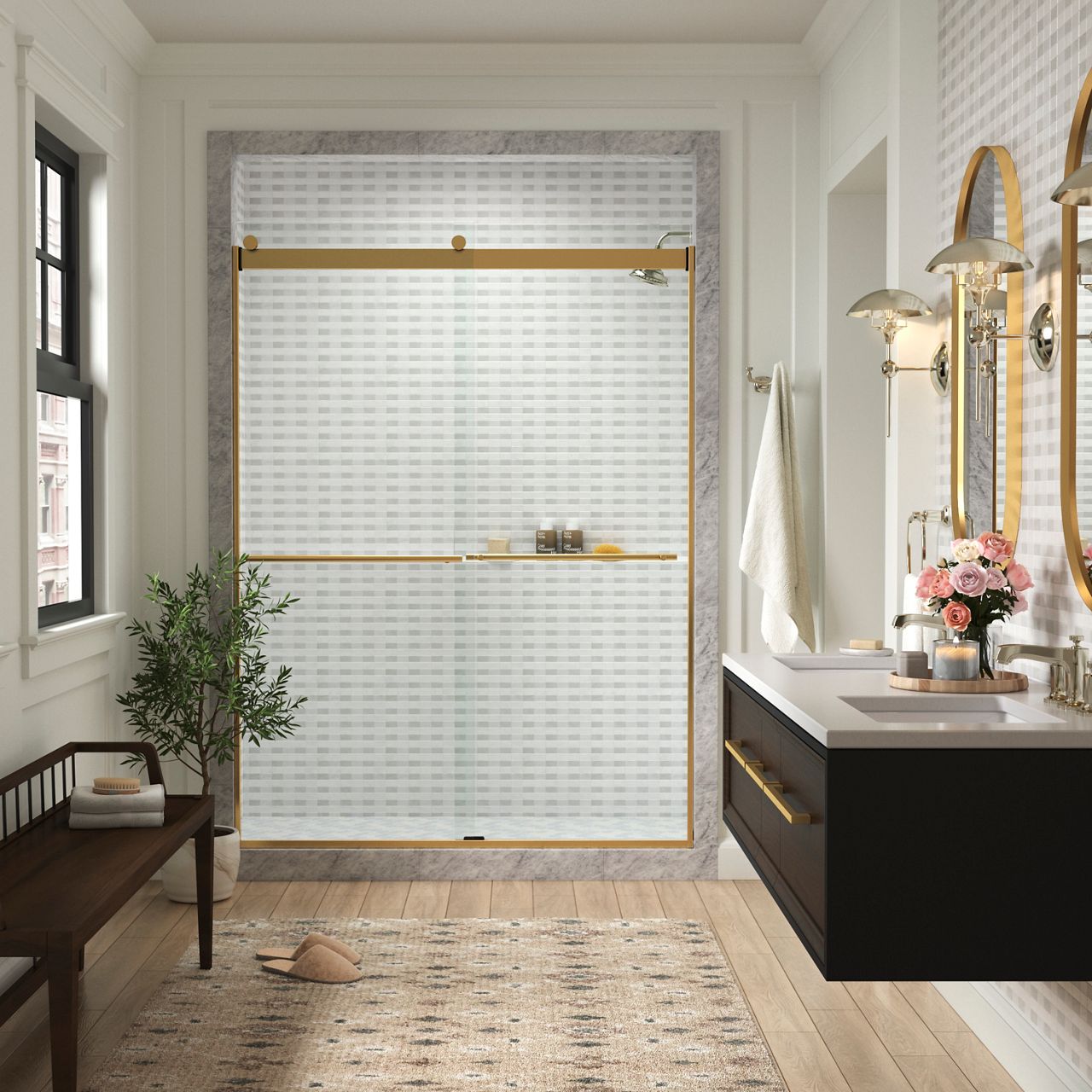 Une salle de bain avec des murs blanc cassé, une fenêtre à gauche avec un petit banc en dessous, une douche au centre avec une porte coulissante en verre en laiton brossé et un meuble-lavabo double mural à droite.