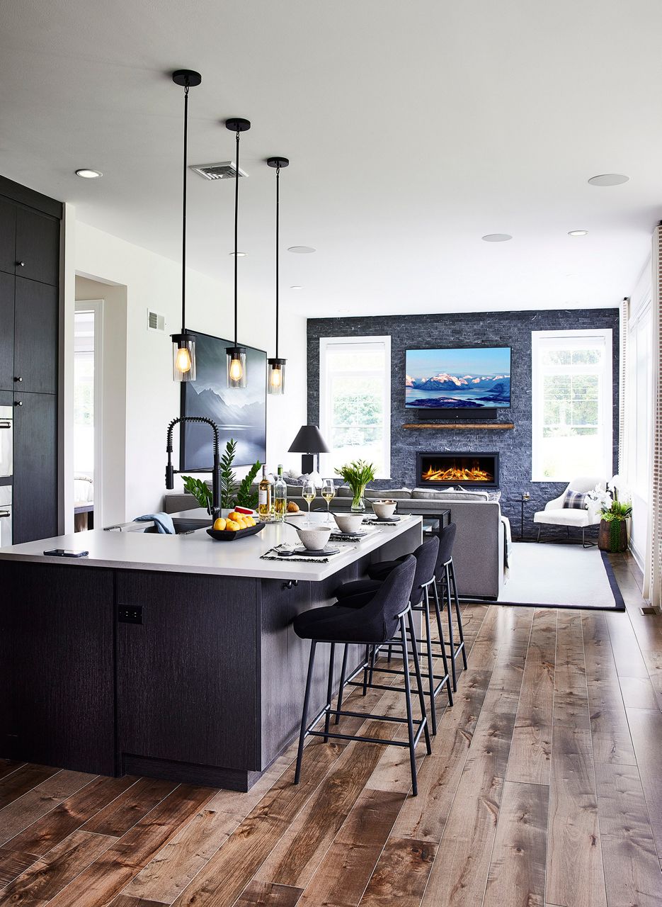 Modern kitchen and living room with island seating and wall-mounted fireplace.