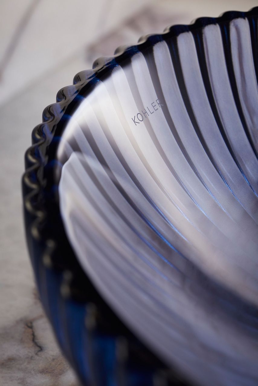 Close-up image of a blue-grey glass vessel sink with ribbed exterior and smooth inside.