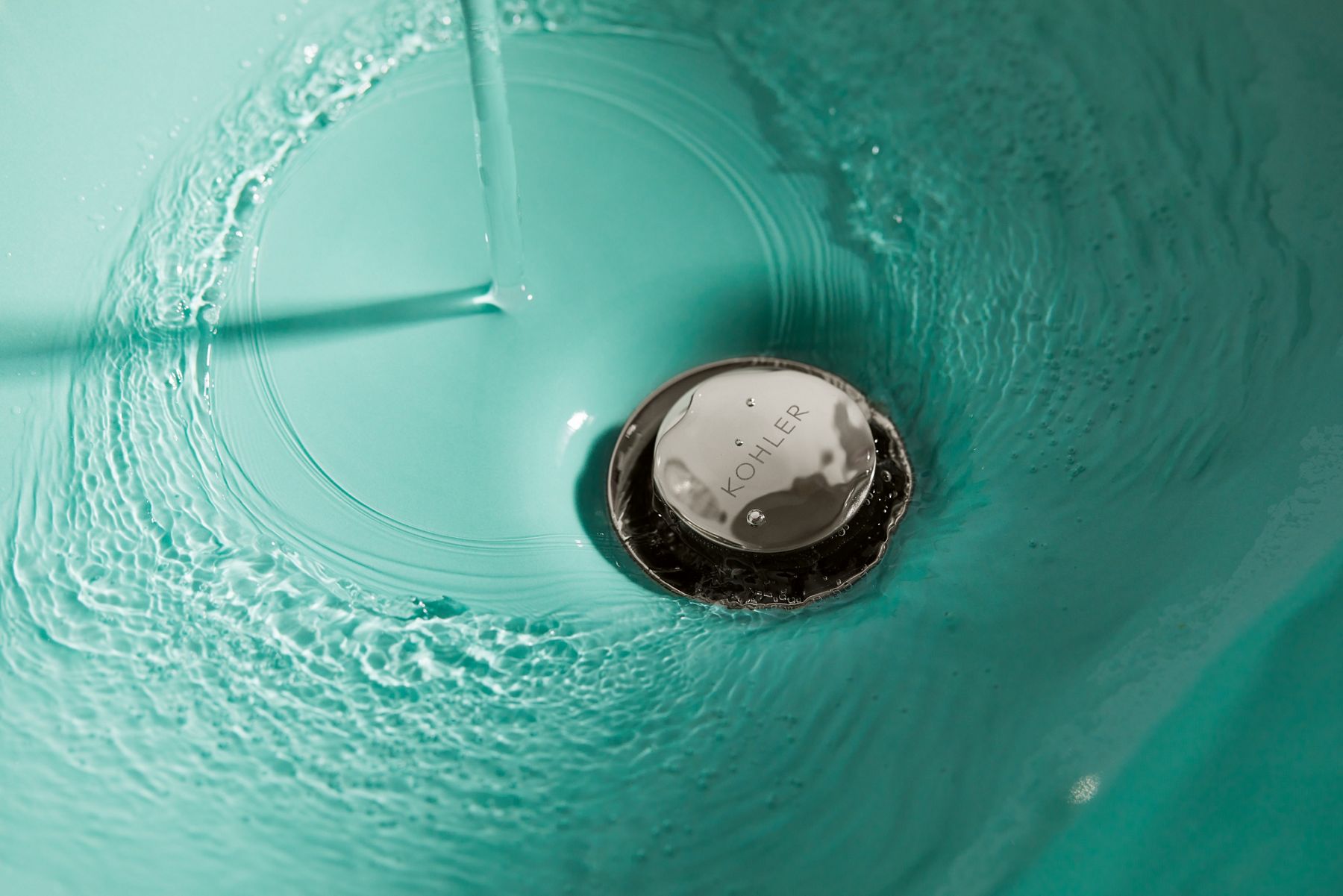 Close-up image of a Spring Green color sink with water swirling around the chrome drain stopper. 