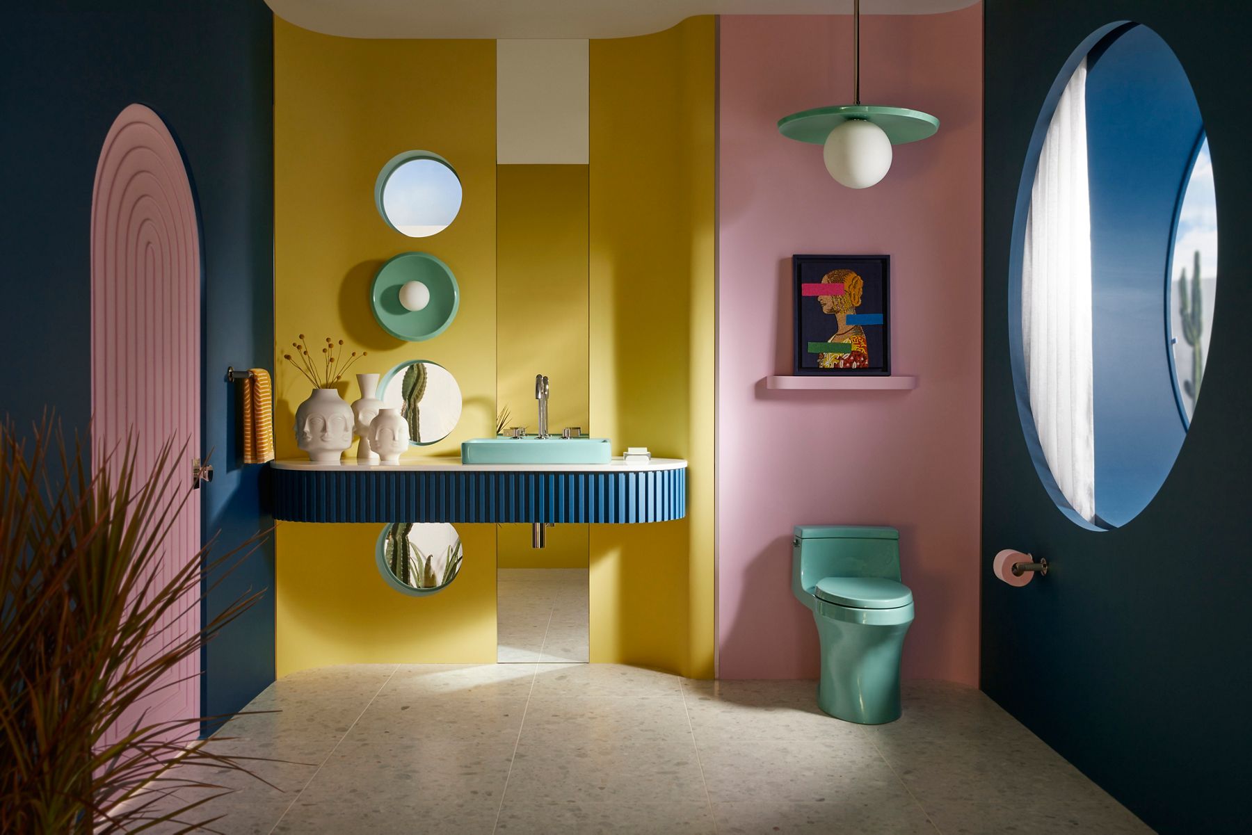 A bathroom designed by Jonathan Adler in an art deco style featuring a toilet sink and lighting shades in a spring green color with saturated pastel hues in the rest of the space.