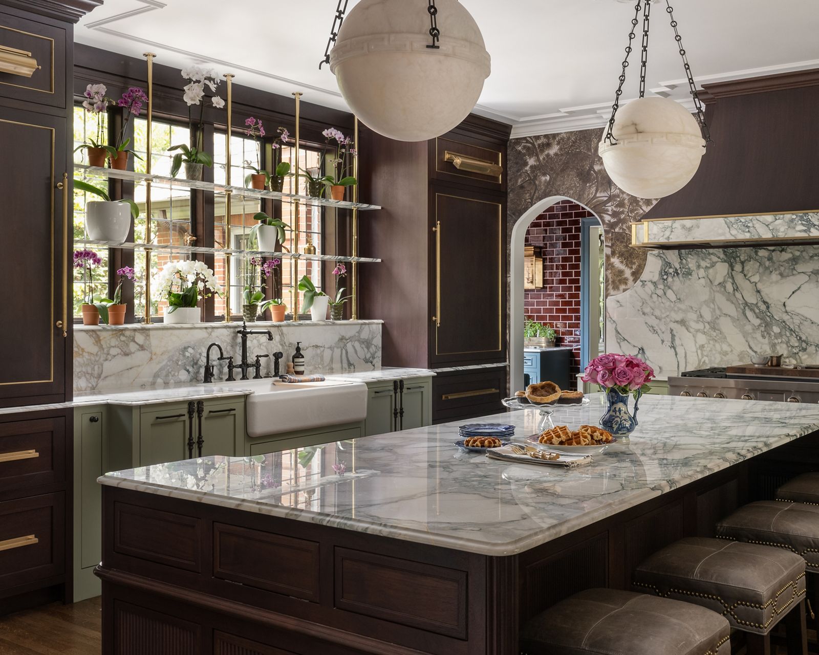 A side-angle view of a white undermount kitchen sink with a chrome faucet, water tap faucet, and spray faucet. There's a light oak wood work station board attached to the right side of the sink with a towel on top. The sink is attached to a white marble countertop with pale green cabinets.