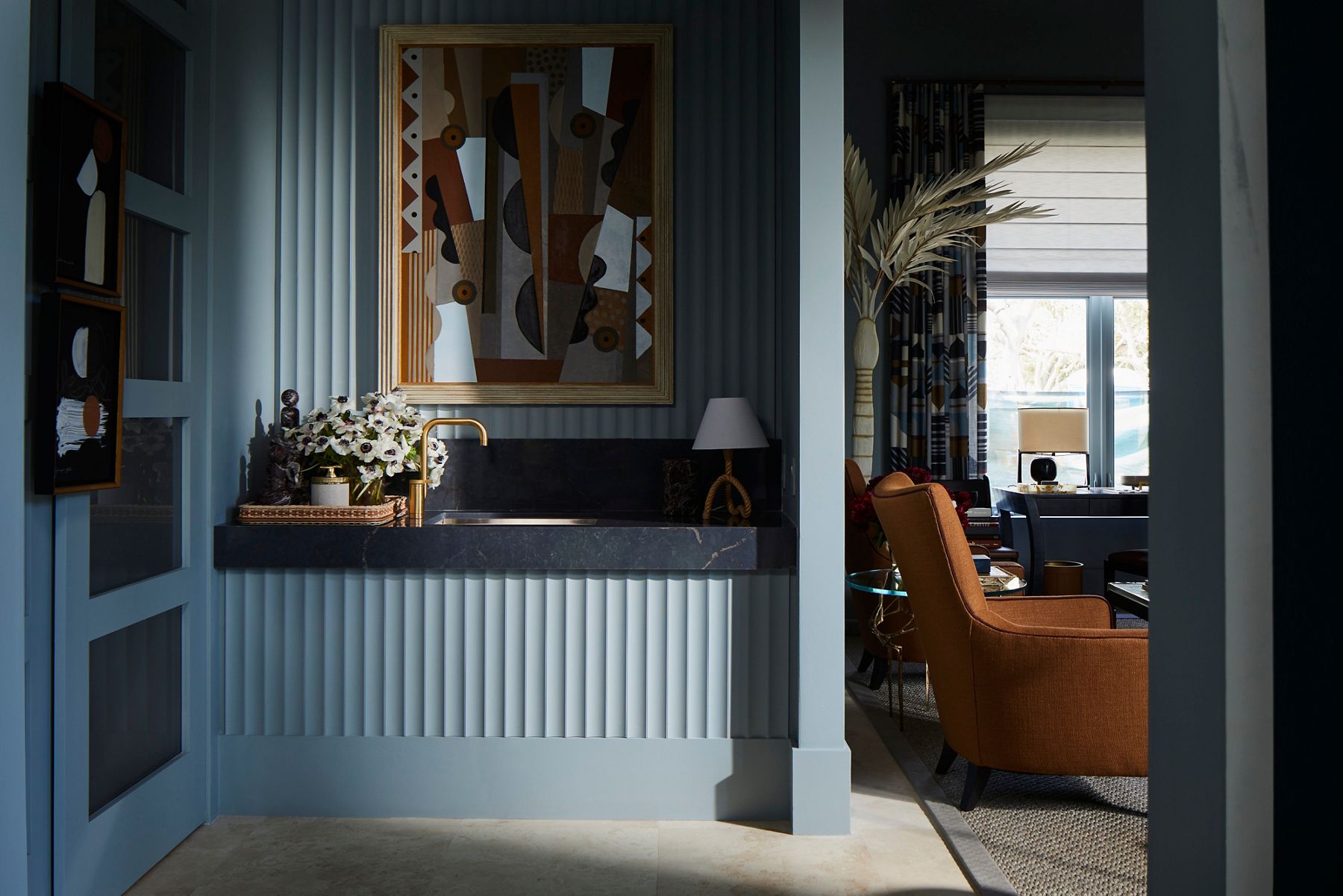 A lounge area in shades of blue and brown with a wet bar area on the left.