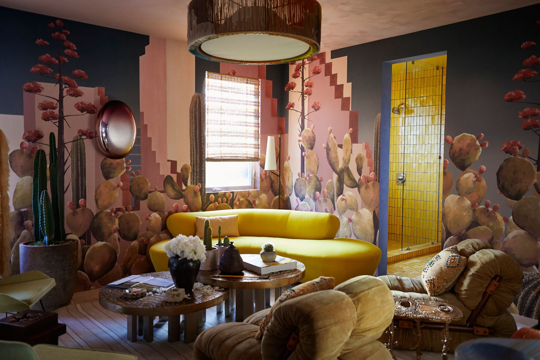 A bathroom lounge in vivid colors with cactus wall paper and bright yellow tile covering the floors and walls of the shower, toilet and vanity areas.