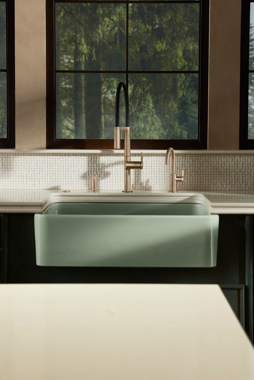 Stainless steel pull-down kitchen faucet with farmhouse sink and tiled backsplash