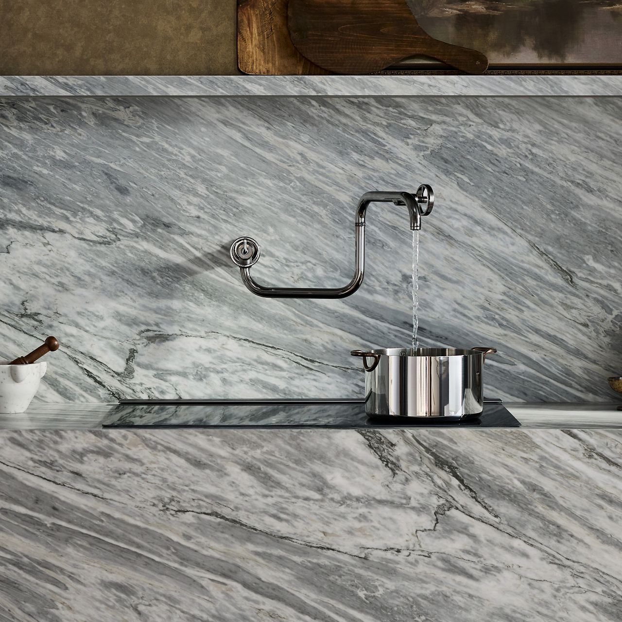 Wall-mounted pot filler faucet extending over a stove with a marble backsplash