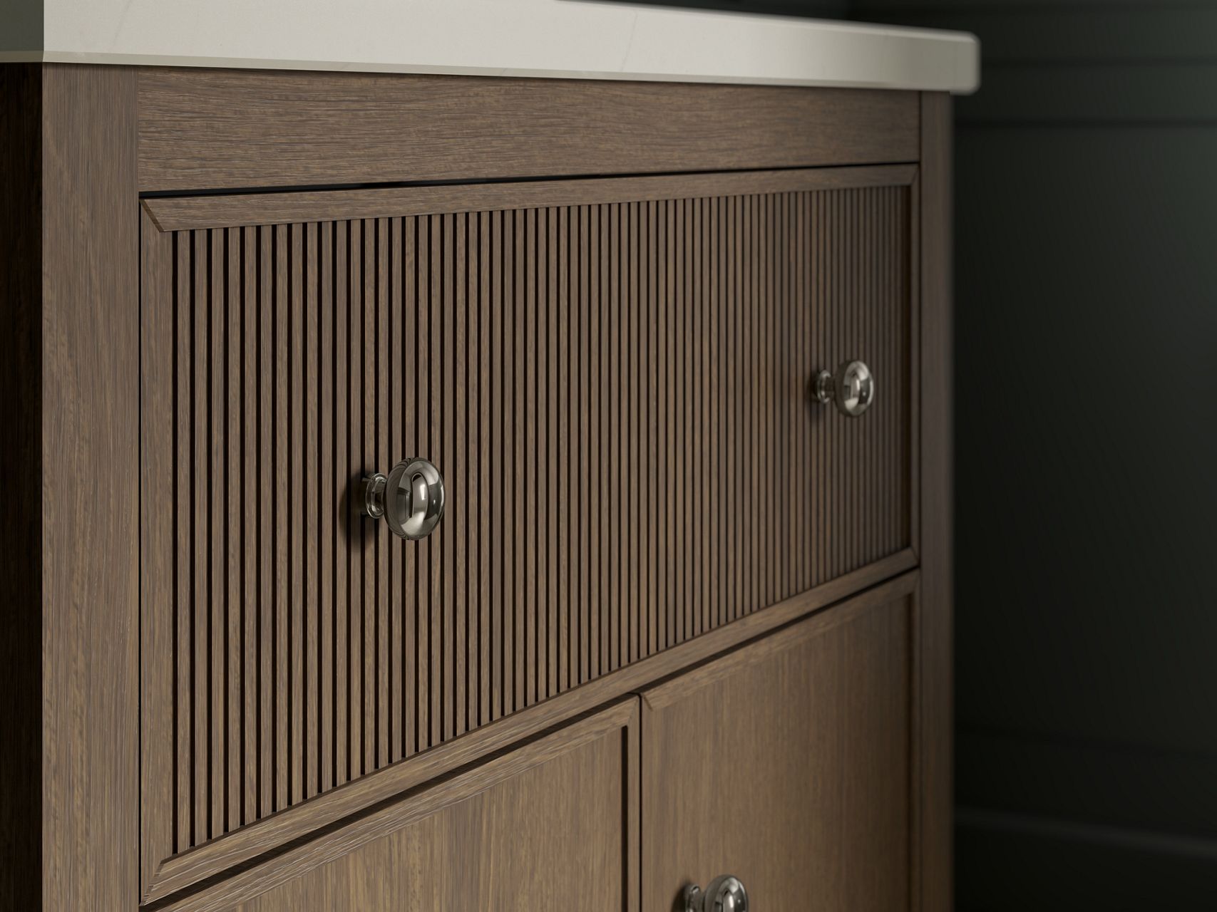 Close-up of wooden vanity cabinet with fluted doors and chrome knobs.