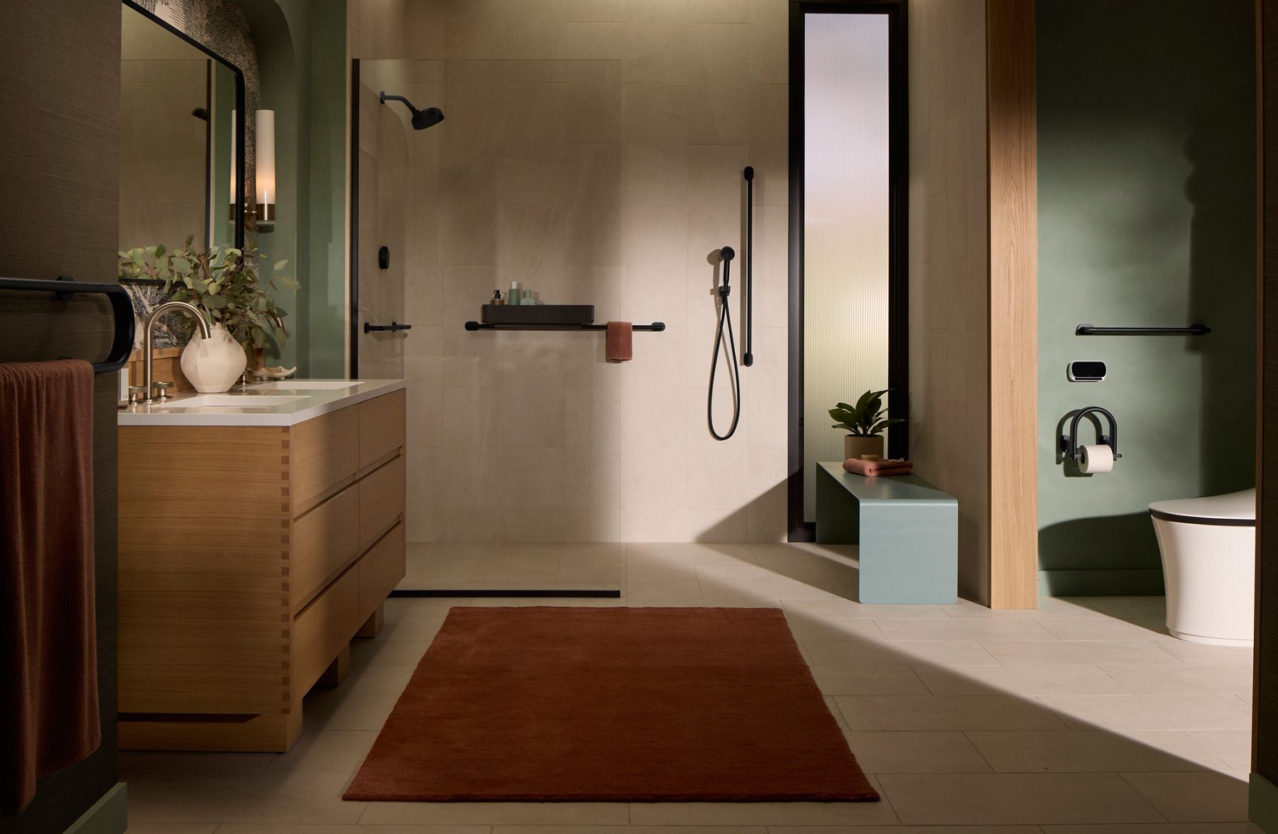 Modern Bathroom with a light wood vanity, large mirror, wall-mounted lighting, walk-in shower with glass divider with minimal decor including plants and a brown floor mat.