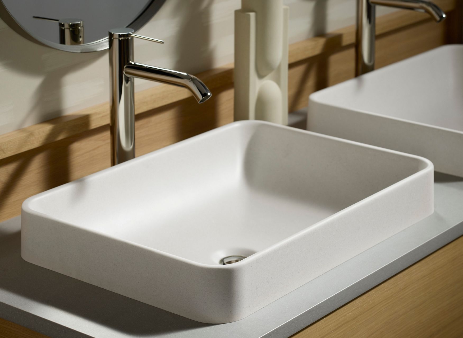 Rectangular white vessel sink on wooden vanity with wall-mounted faucet