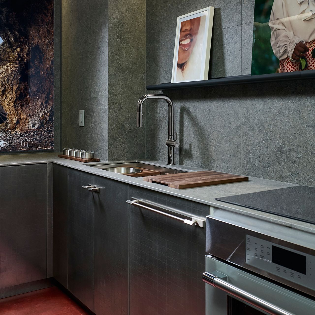 Modern kitchen with dark textured cabinetry, integrated stainless steel appliances, a sleek countertop with cutting board, and minimalist décor.