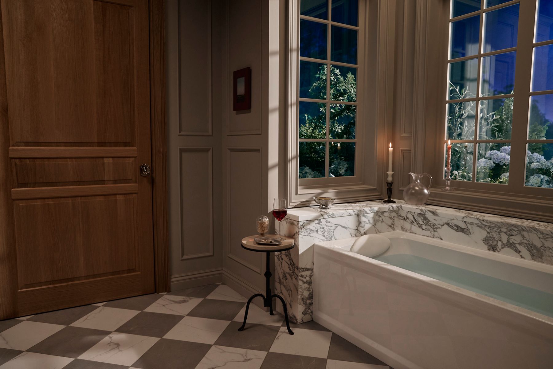 Luxury bathroom featuring a rectangular drop-in bathtub with a marble surround, large windows, and candlelit accents creating a relaxing spa-like atmosphere.