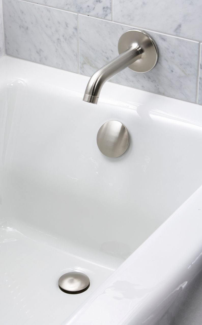 A white bathtub with brushed nickel faucet and light gray mottled stone tile walls.