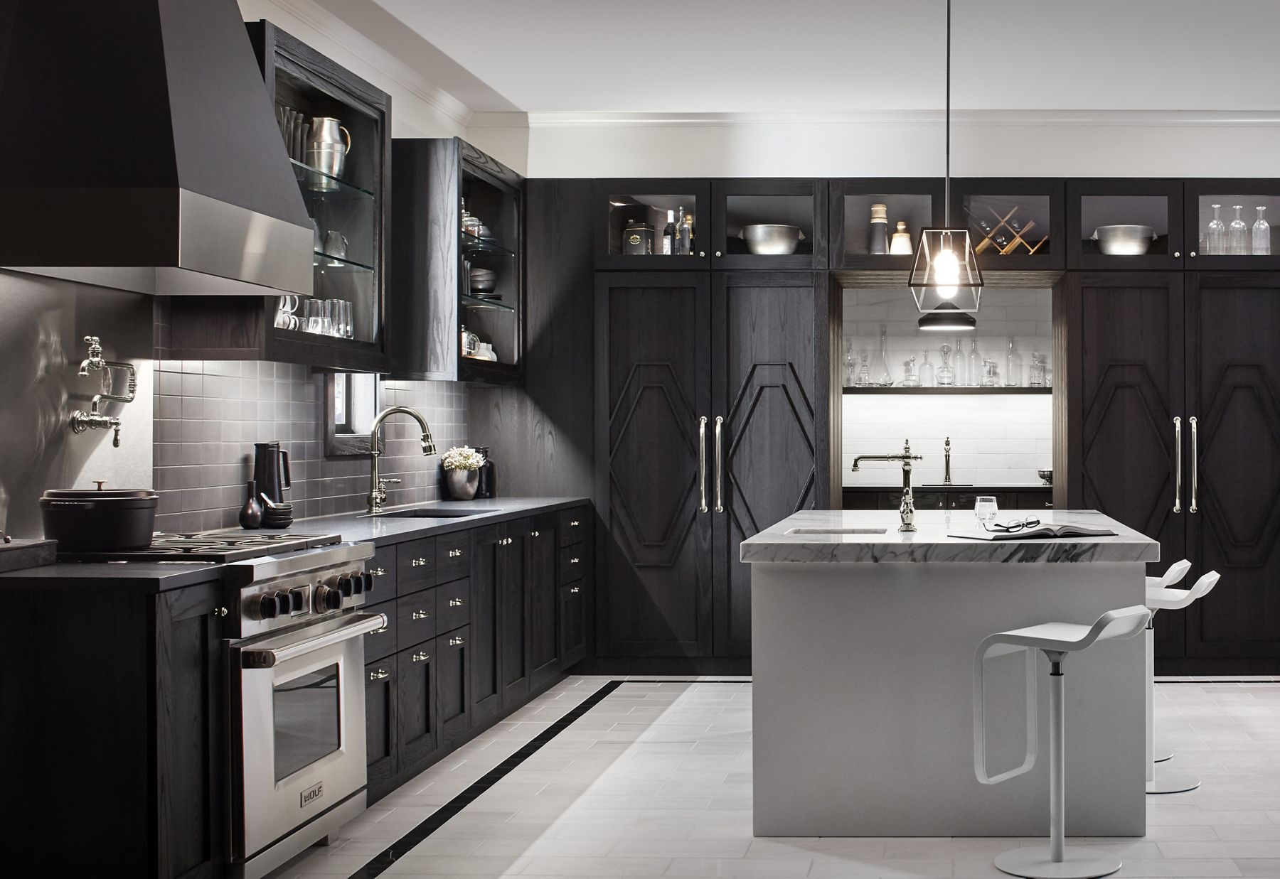 In a black and white kitchen with large island, modern cabinetry contrasts with the traditional lines of the KOHLER Artifacts pot filler, kitchen sink faucet, and bar sink faucet with Victorian spout design.