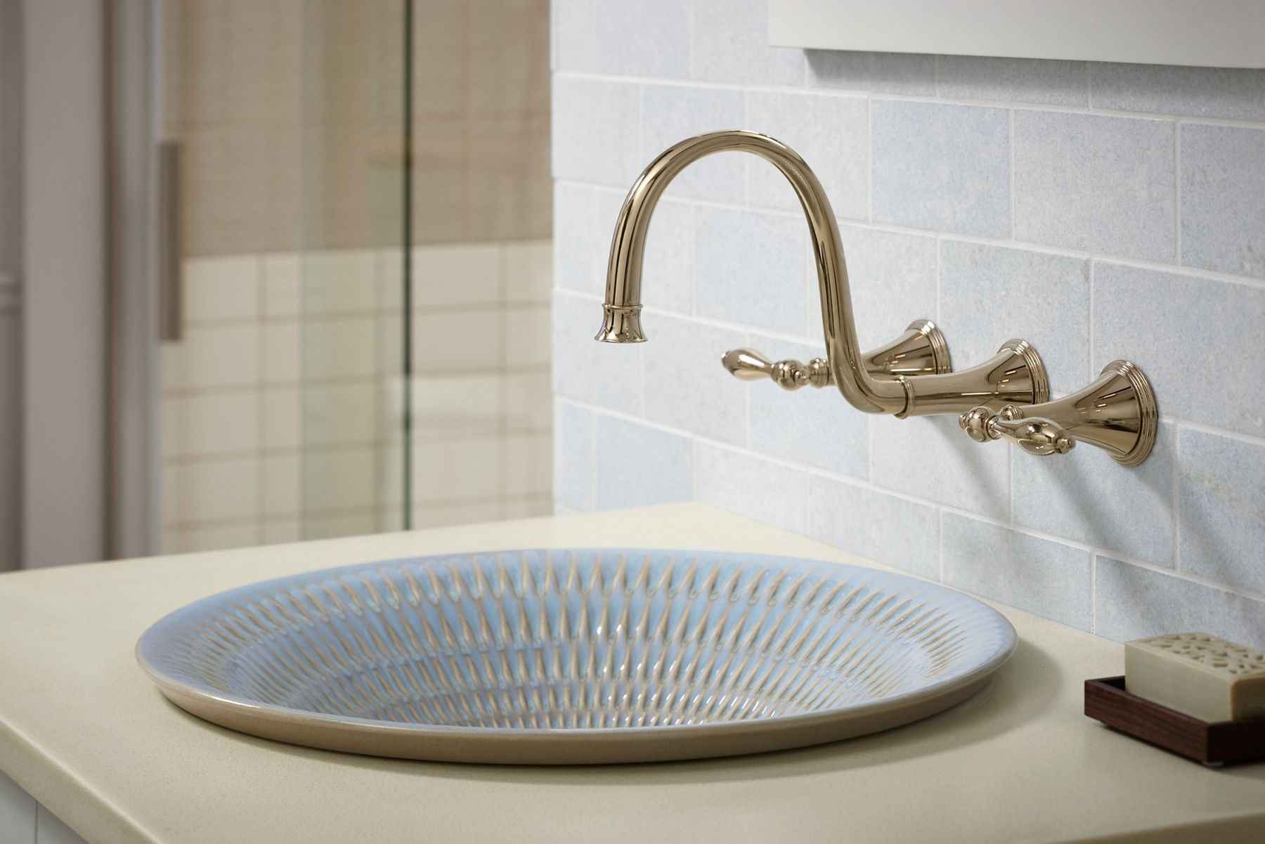 Black textured vessel sink with brass wall-mounted faucet