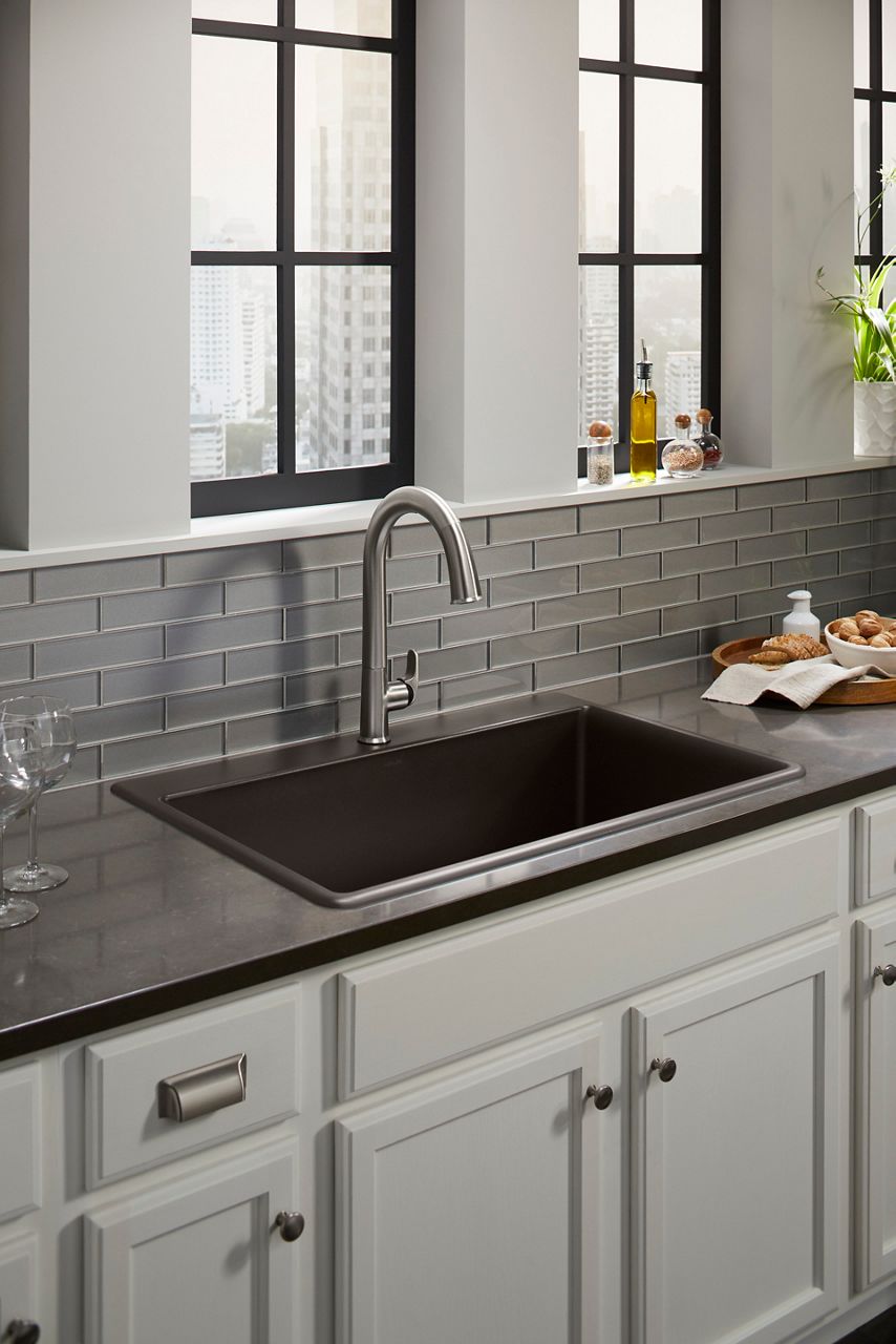 Stainless steel pull-down kitchen faucet with black sink and gray tile backsplash