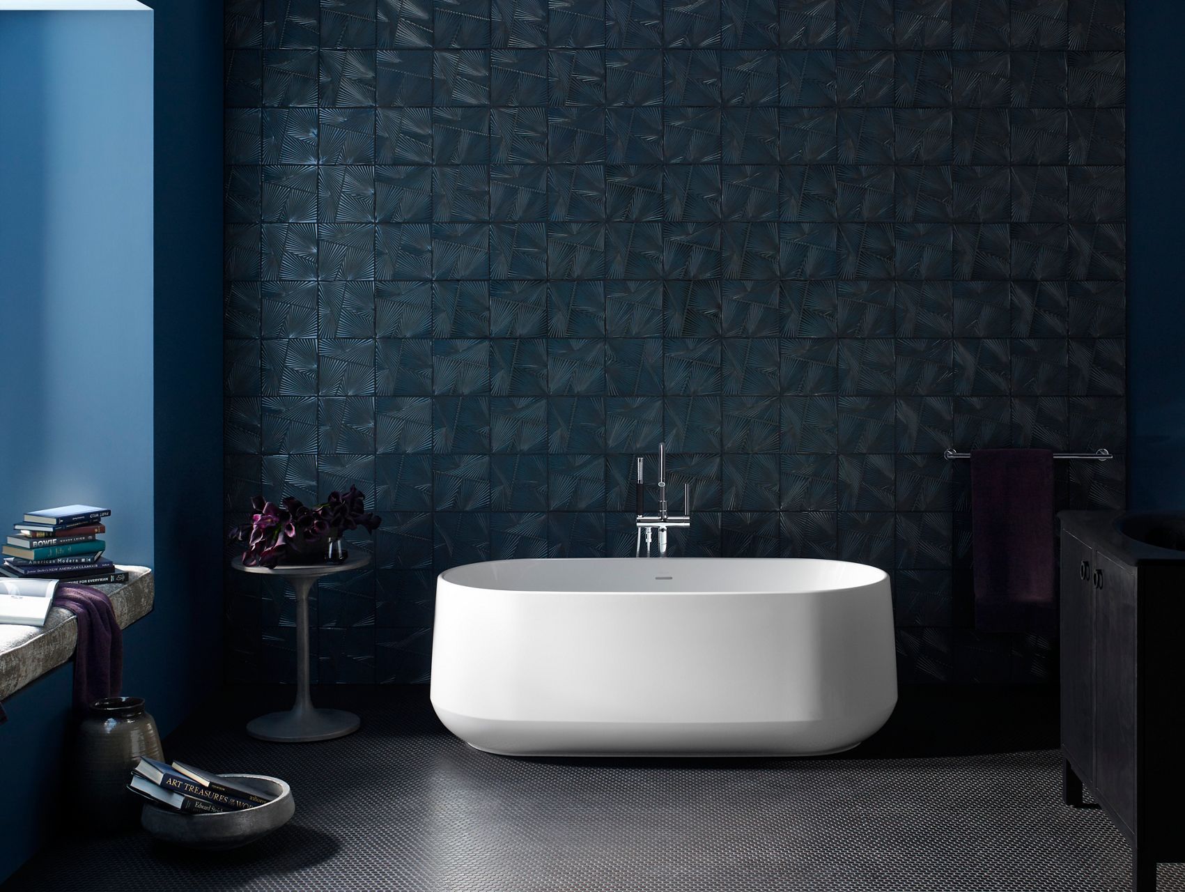 A Ceric freestanding bath in a room with dark walls.