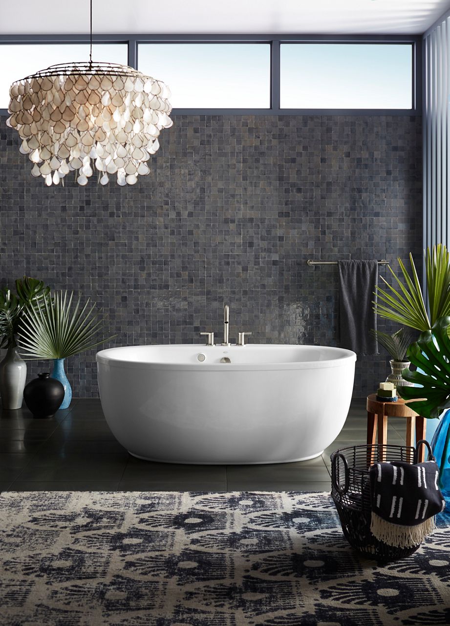 A Sunstruck freestanding bath in a room with dark walls.
