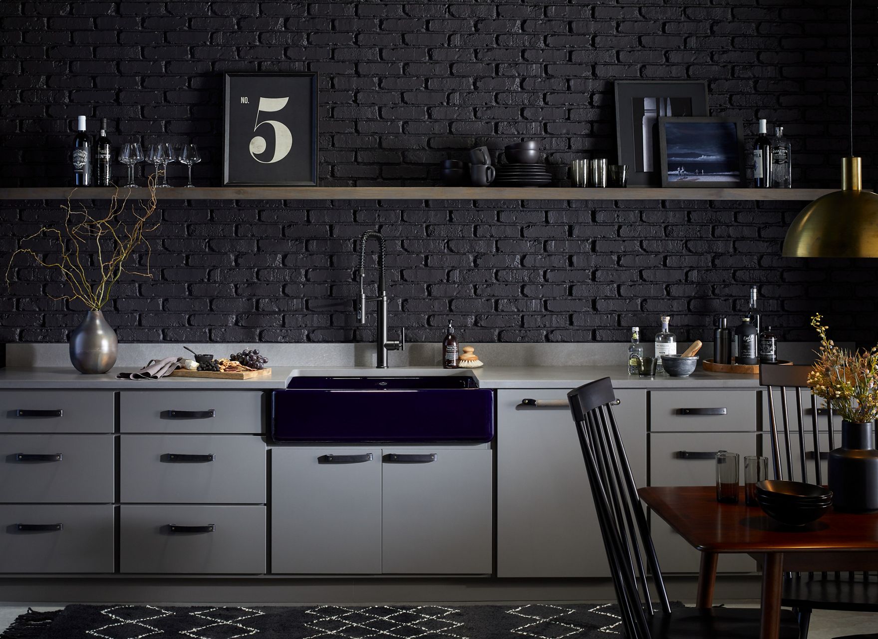 A kitchen with black brick wall, open shelving above white cabinets, KOHLER Whitehaven farmhouse sink in Indigo blue, and Purist Semi-professional kitchen sink faucet.