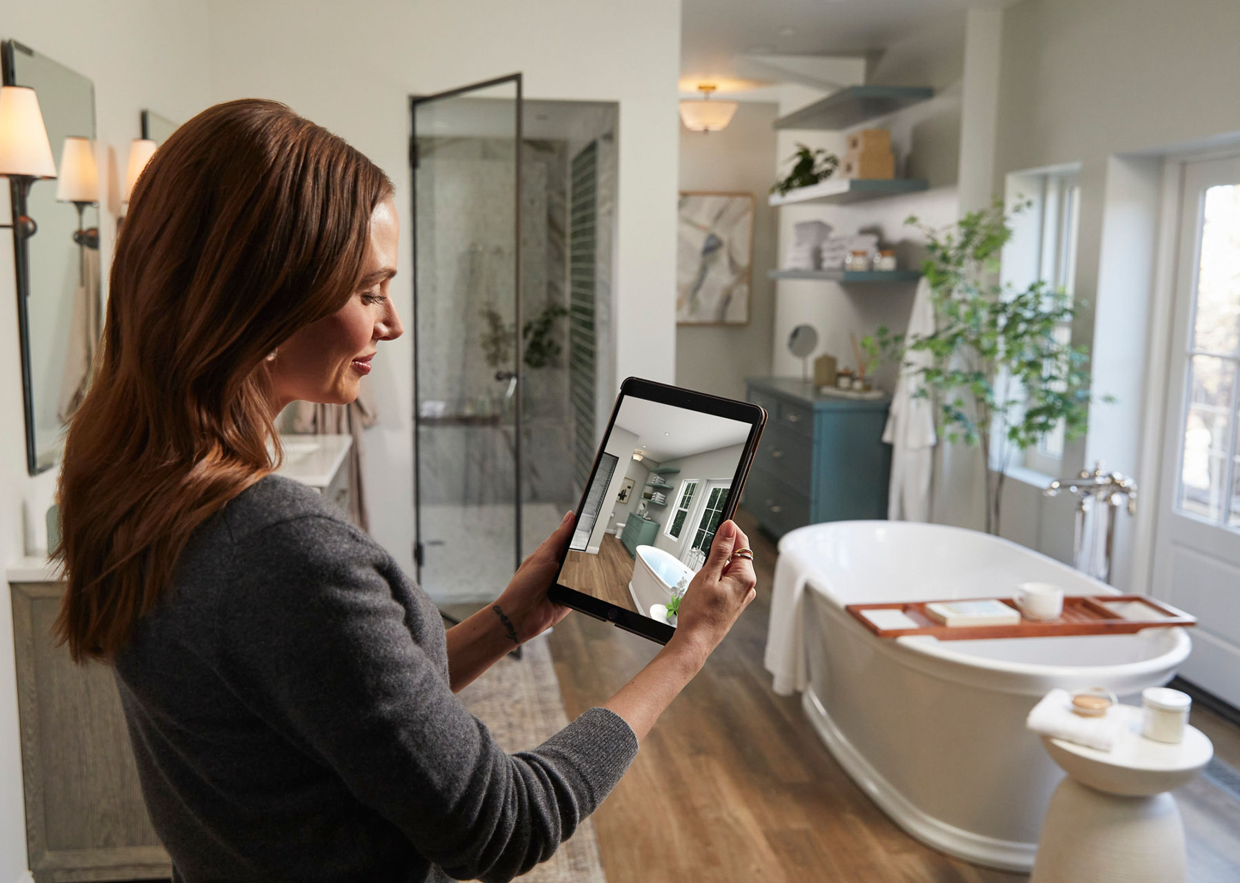 An image of a woman looking at a photo of her bathroom with the text ‘Bathroom Design Services – Get Started’