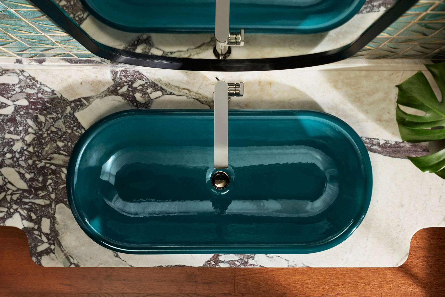 Oval-shaped cast iron sink with a glossy black finish, showcasing Kohler's use of 80% recycled materials in fixtures.