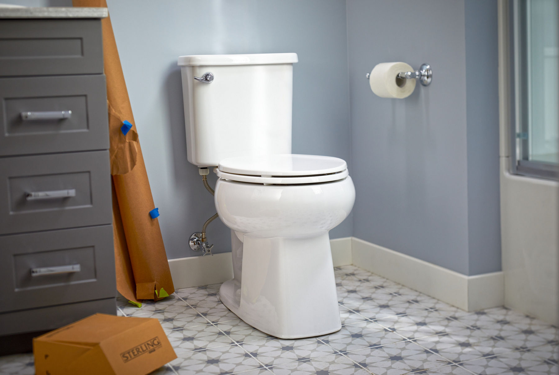 A white toilet against a blue wall with tile flooring.