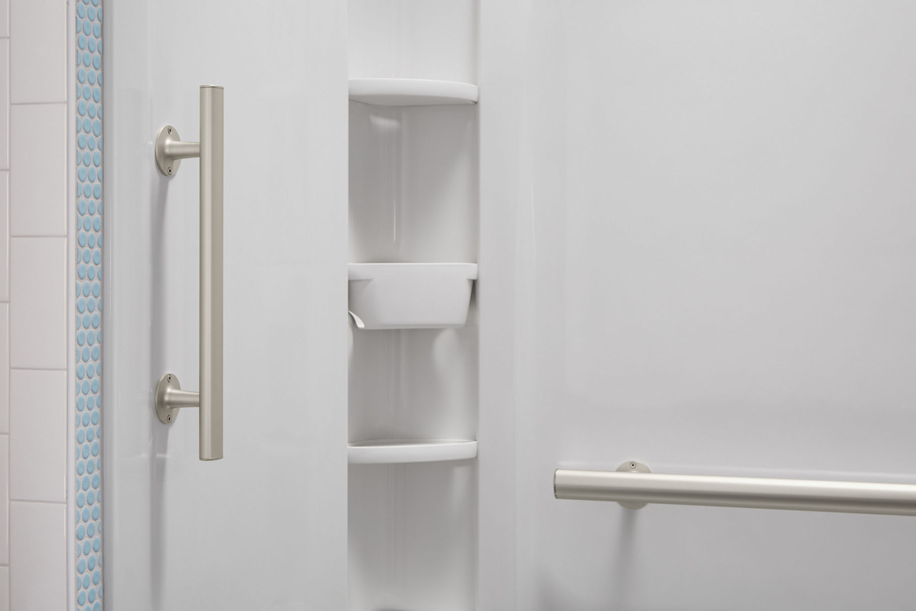 A white shower area with vertical and horizontal grab bars.