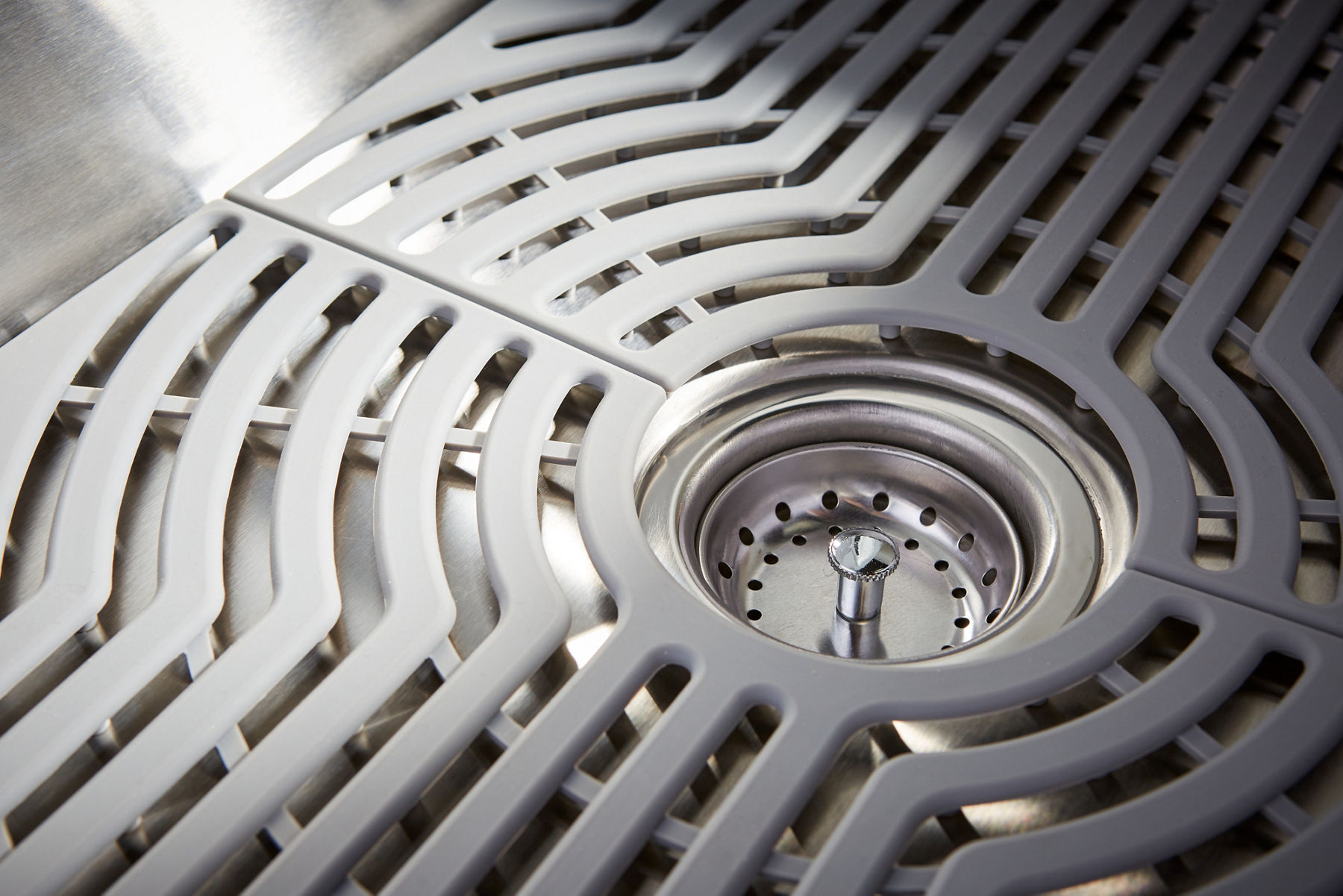 Close up detail of a rack sitting on the bottom of a sink with a cutout for the drain.