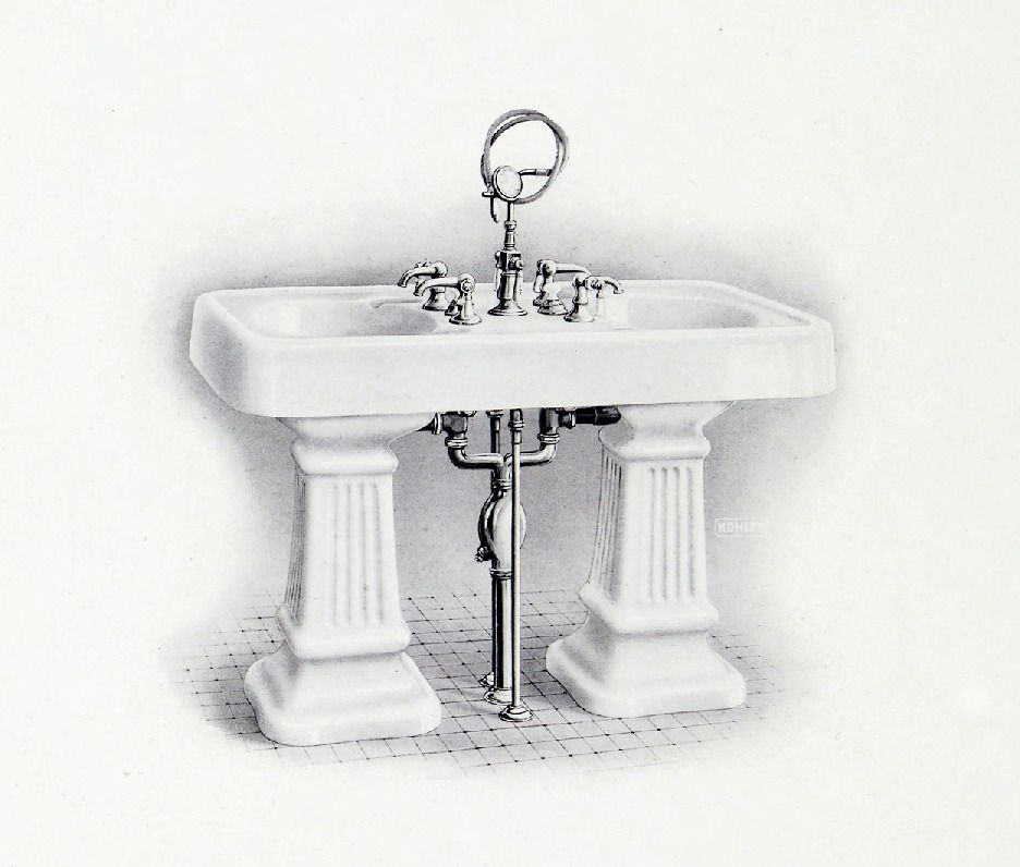 A historical black and white image of two pedestal sinks back to back and connected at the top.