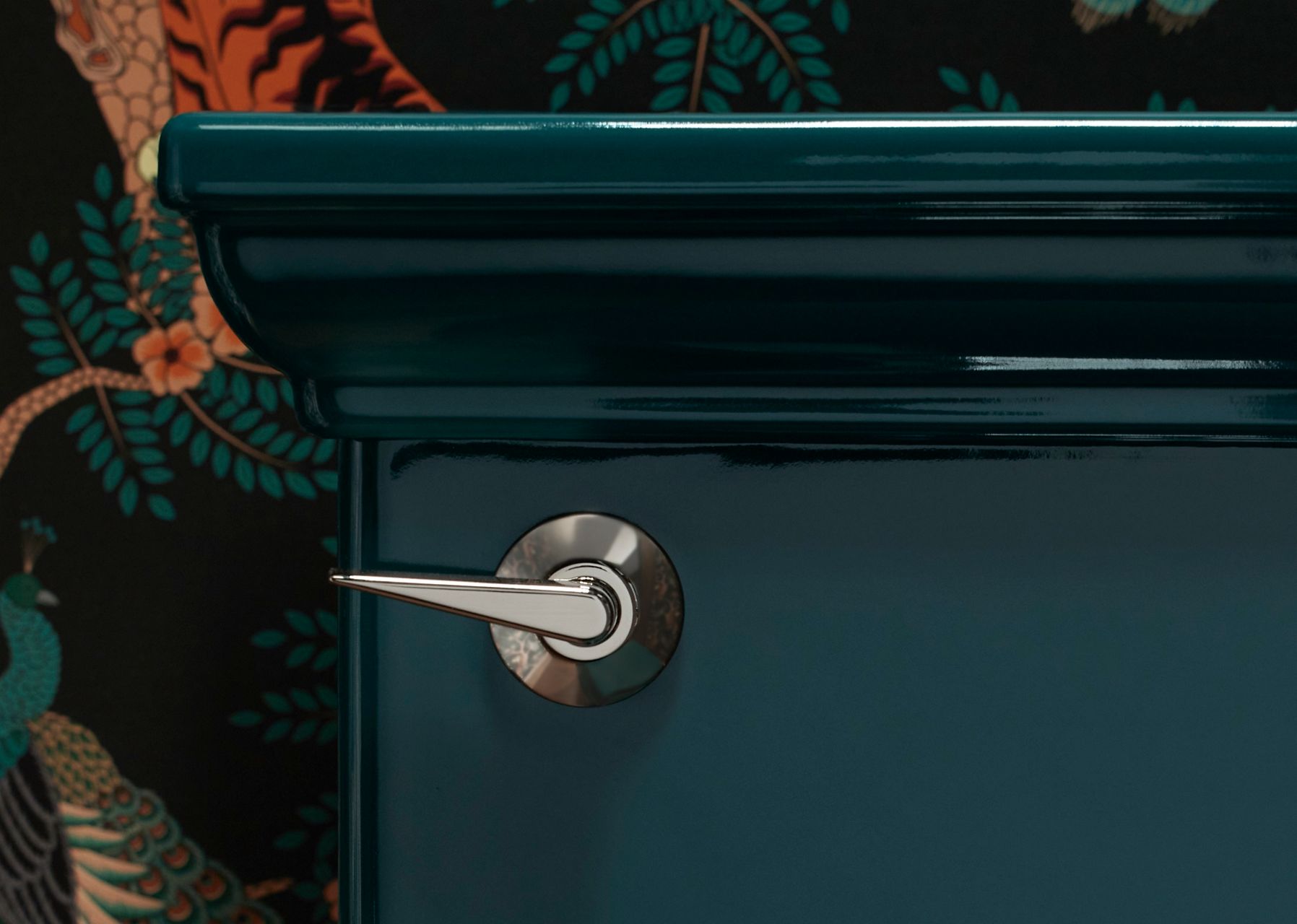 A close up up a silver handle on a bathroom teal blue vanity.
