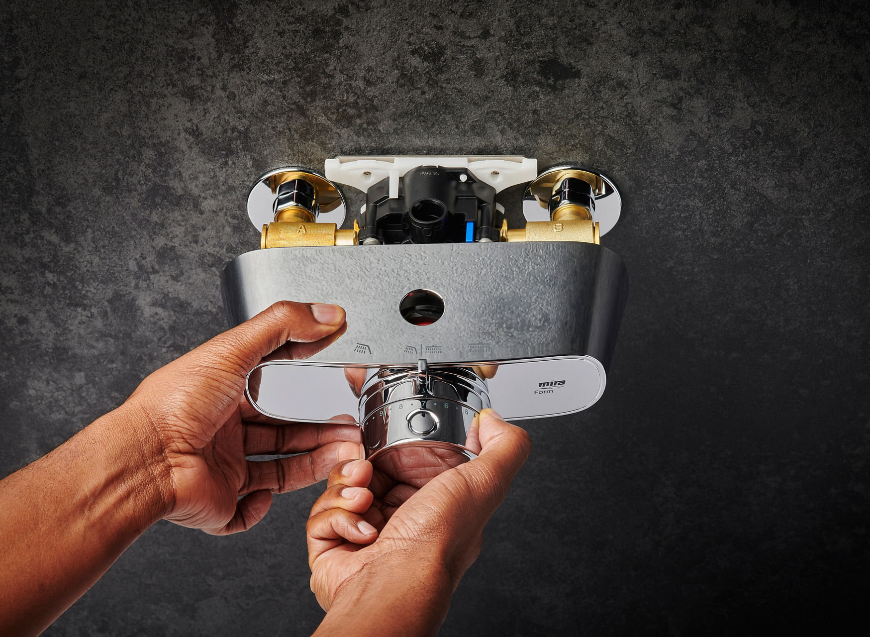 A Form Mixer Shower being installed on a grey coloured wall.