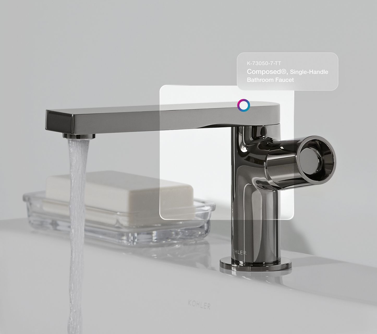 A Composed faucet in titanium finish pouring water into a white sink.