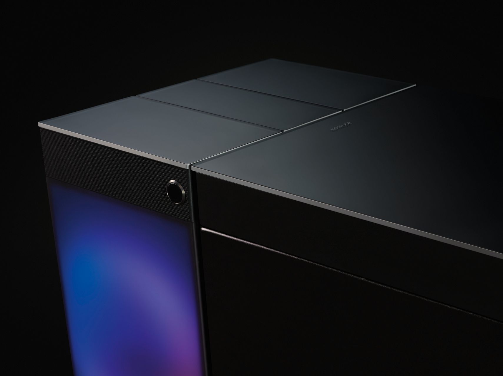 The top of a square black smart toilet with an illuminated back panel in a darkened room.