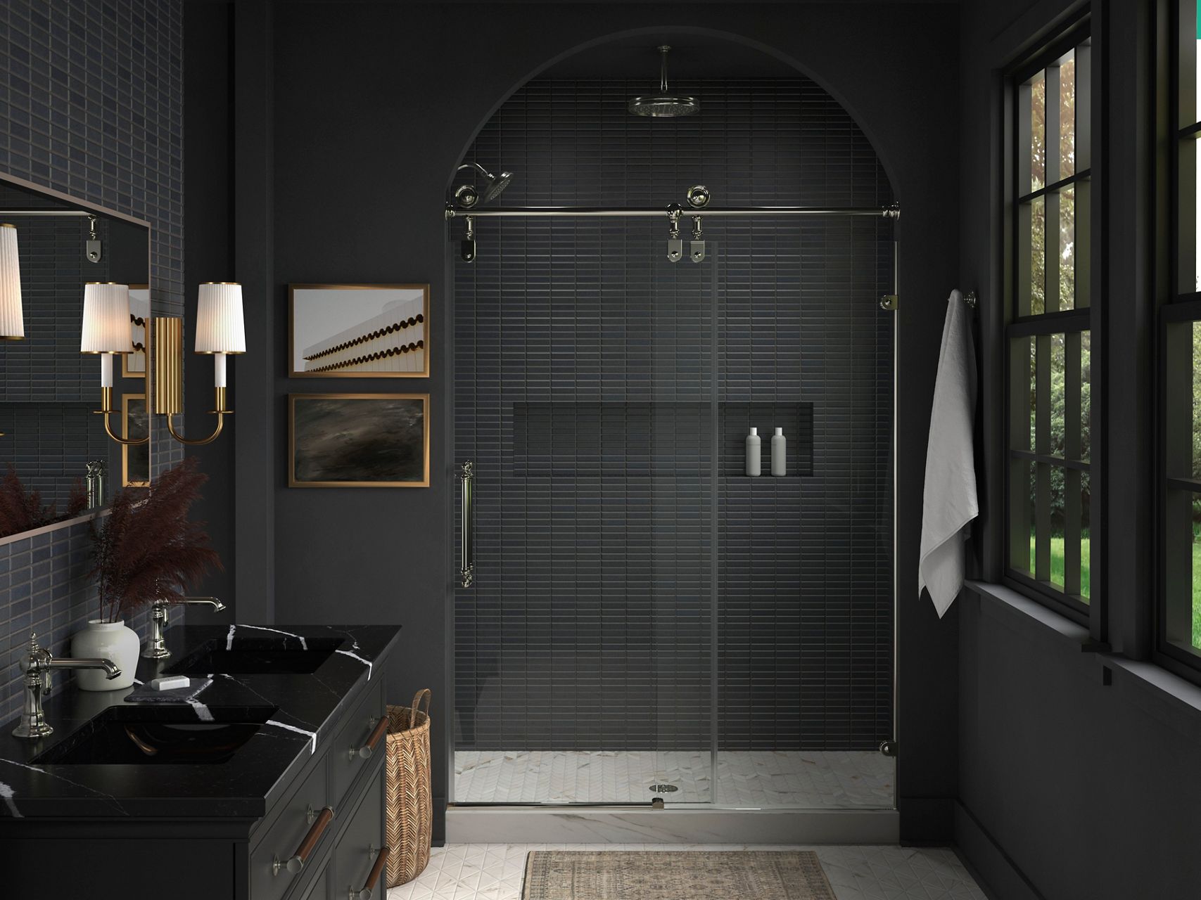 A bathroom with dark gray tile walls, a double vanity with a black counter top and a shower area sharing a combination of polished chrome and brushed brass finishes.