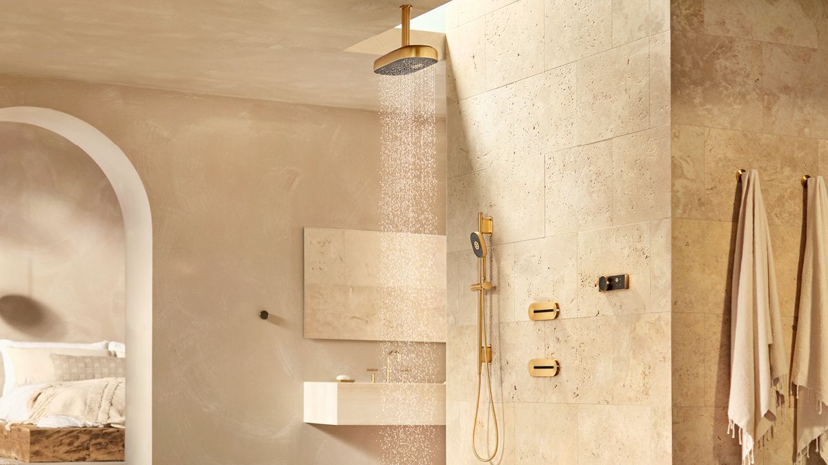 A modern, neutral bathroom with a running rain head and gold-tone shower valve and trim.