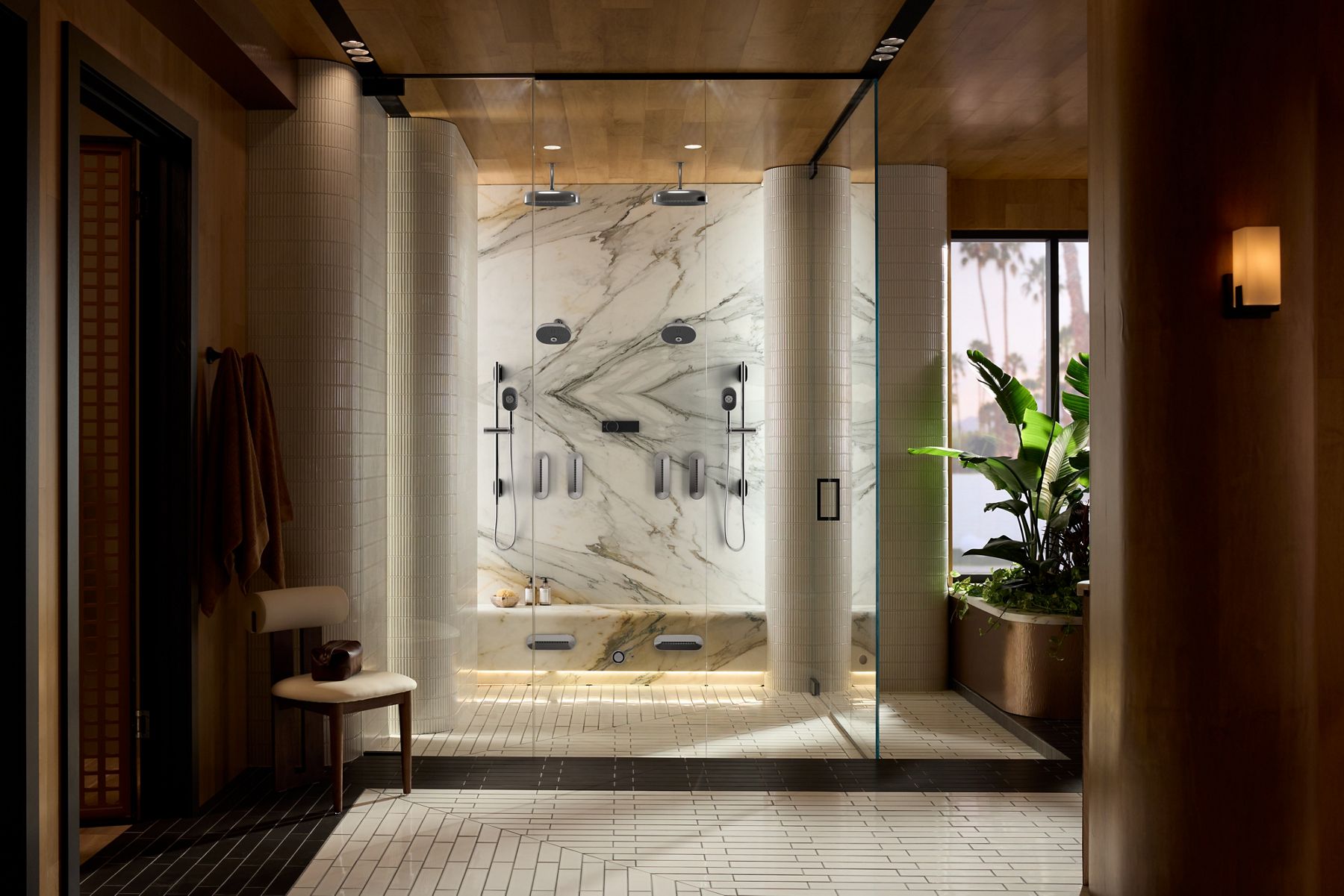 The exterior of a walk in shower with glass shower doors, and two showerheads and rainheads.