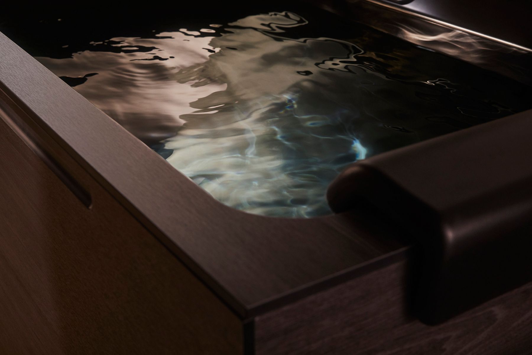 Close-up of a dark ice bath filled with rippling water, featuring the text 'Wellness at 39°F' and a prompt to explore cold immersion therapy by Kohler x Remedy Place.