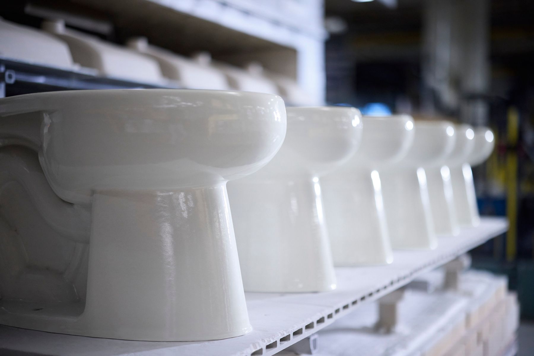 A row of KOHLER Toilets on display in a manufacturing facility.