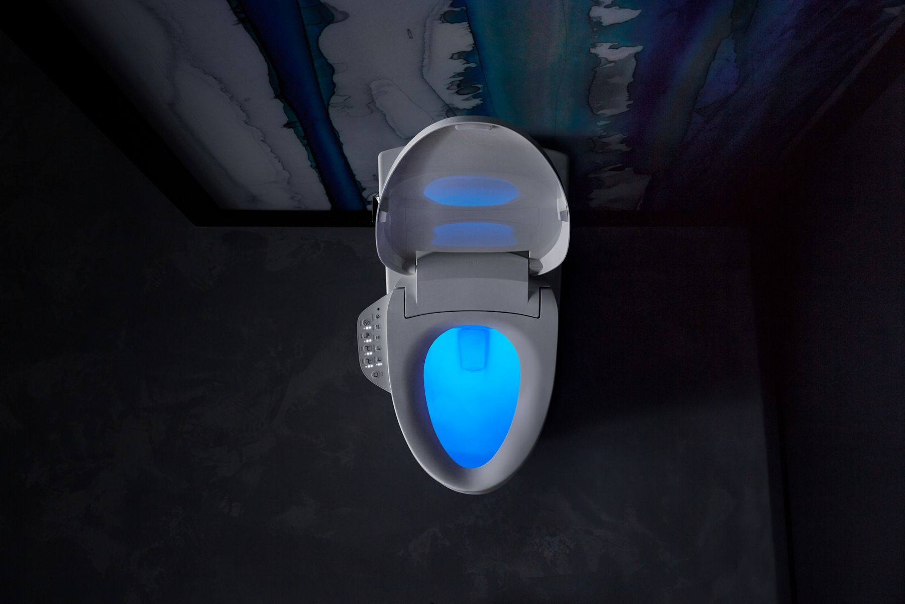 Overhead view of a toilet with a bidet seat with the lid open and a blue nightlight glowing within the bowl.