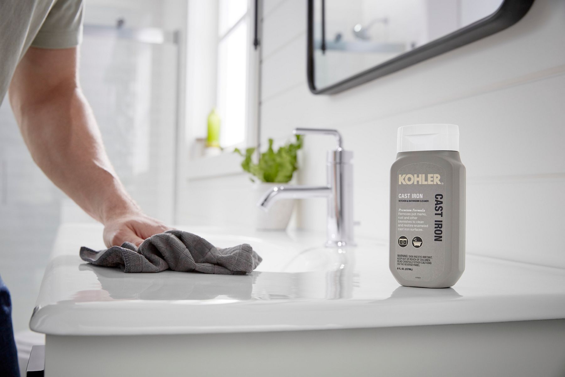 A man cleans a cast iron bathroom sink with KOHLER cast iron cleaning product.
