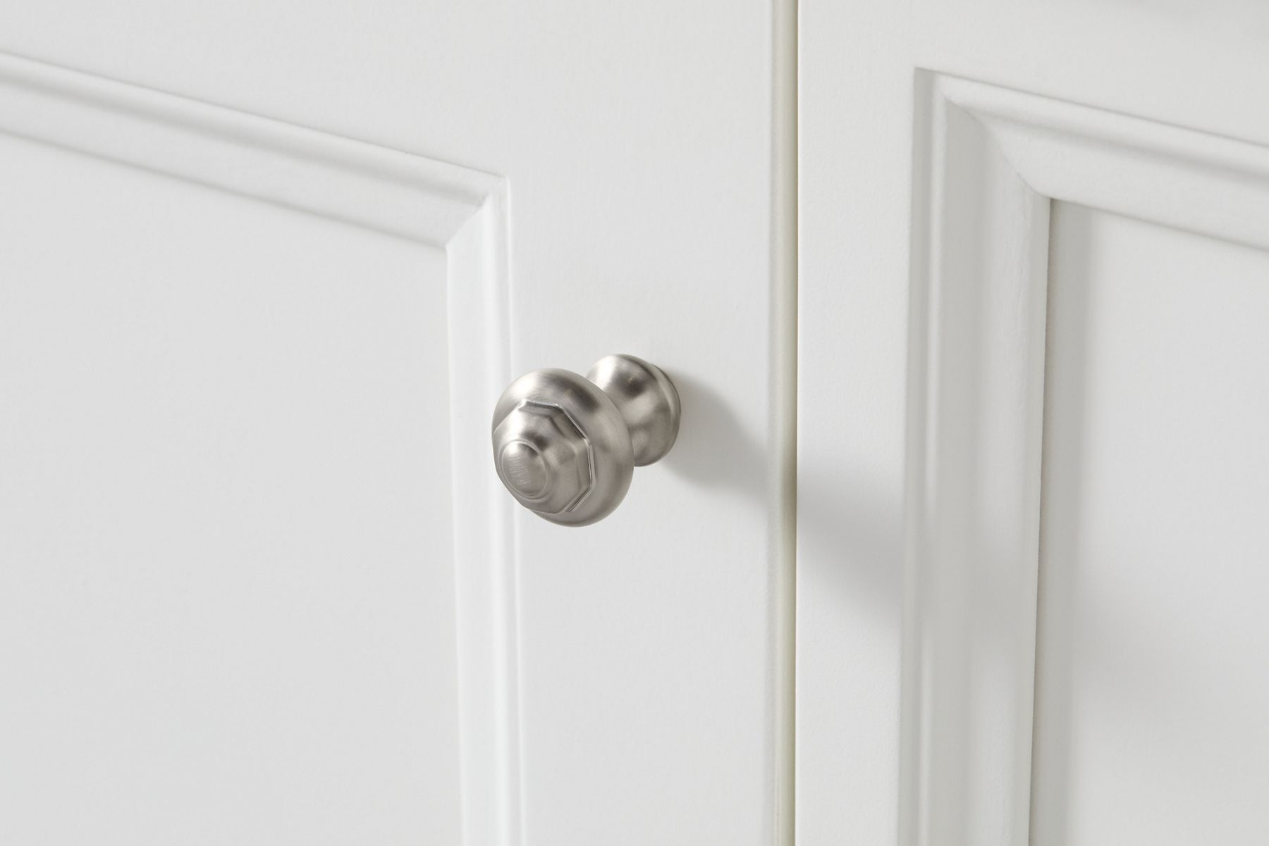 A KOHLER Artifacts cabinet knob on a white vanity door.