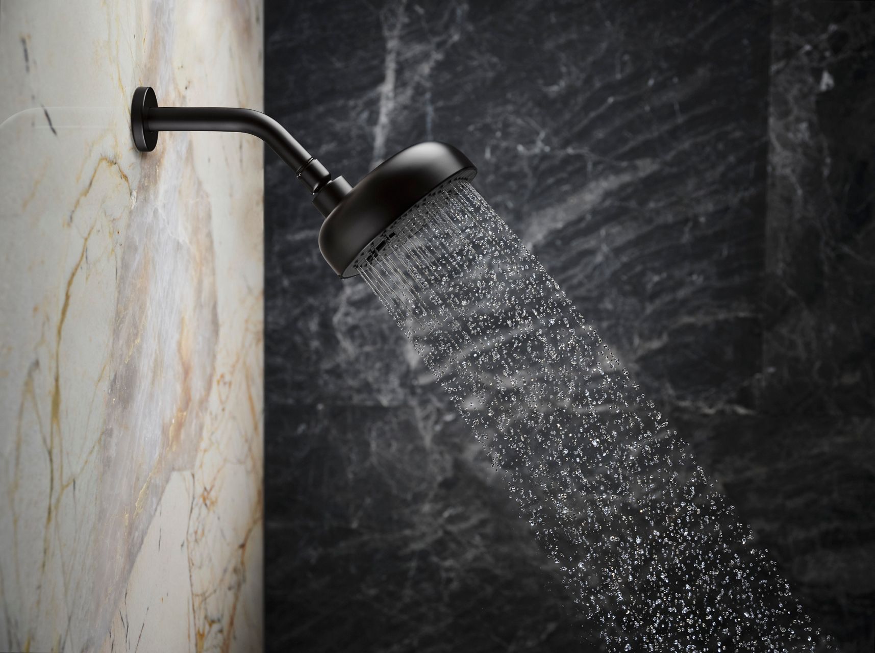 Close-up of a matte black showerhead mounted on a wooden-textured wall, emitting water in a modern bathroom setting