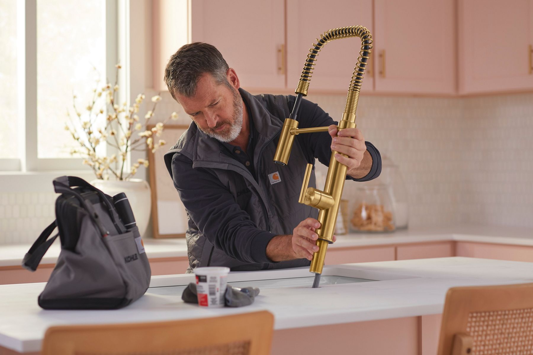 A plumber installs a semi professional kitchen faucet in a kitchen island sink. 